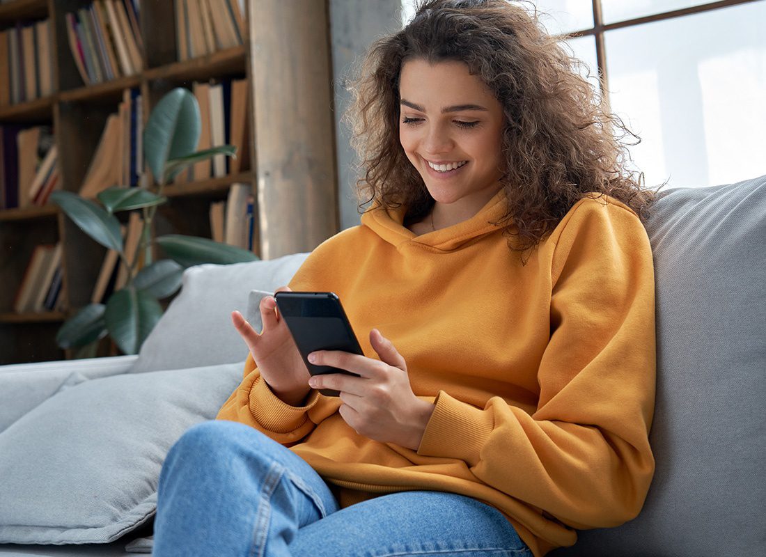 Read Our Reviews - Young Teenage Girl Checks Her Social Media While Holding Her Smartphone